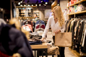 Beautiful young woman with shopping bags standing at the clothing store